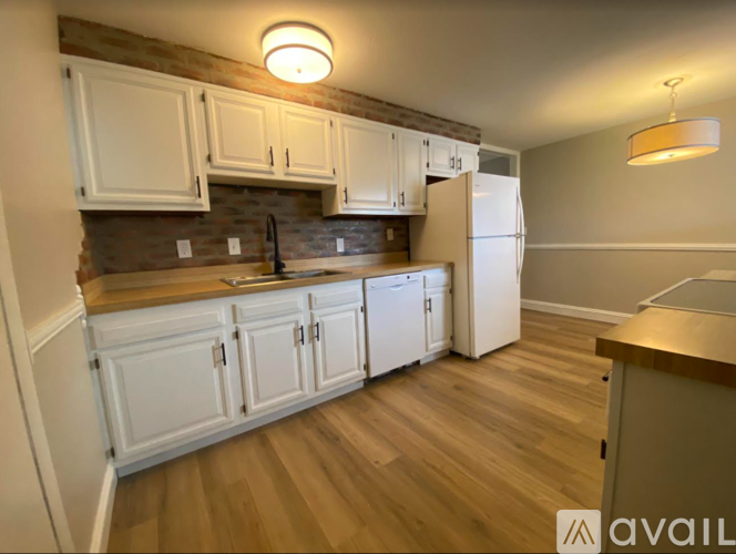A kitchen with white cabinets and a wooden floor.