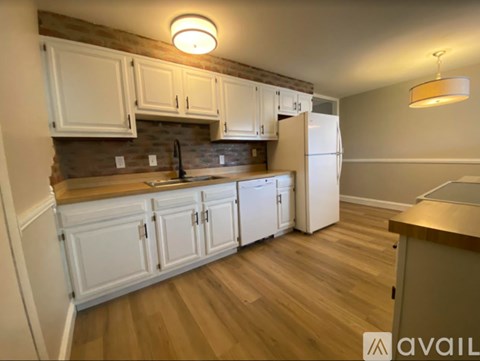 A kitchen with white cabinets and a wooden floor.