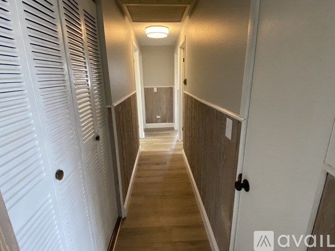 A long hallway with white doors on the left and brown doors on the right.