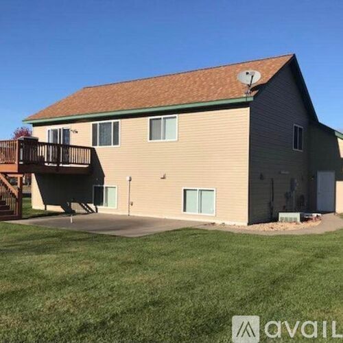 A house with a brown roof and a deck in front.