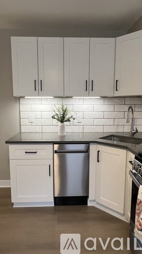 A kitchen with white cabinets and a black countertop.