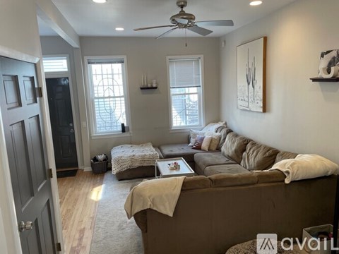 A living room with a brown couch and a ceiling fan.