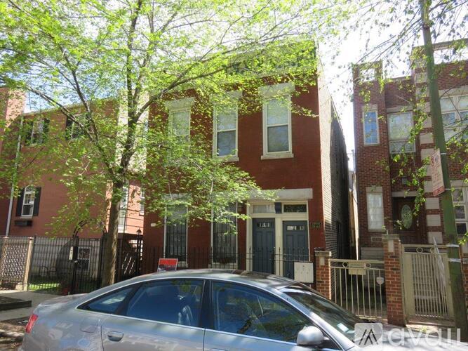 A silver car is parked in front of a red brick building.