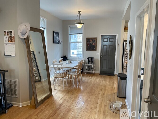 A dining room with a wooden floor and a white table with chairs.