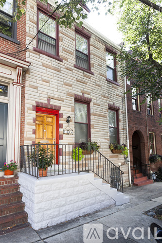 A brick building with a red door and a black railing.