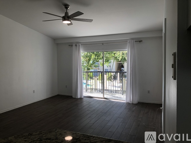 A room with a ceiling fan and sliding glass doors leading to a balcony.