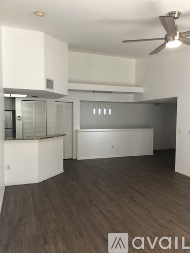 A spacious room with a ceiling fan and wooden flooring.