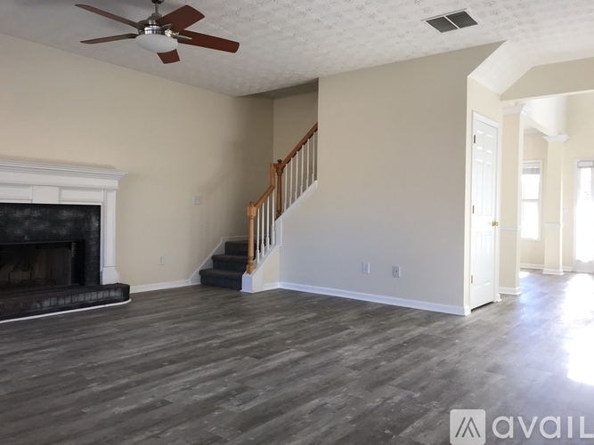 A spacious living room with a fireplace and a staircase.