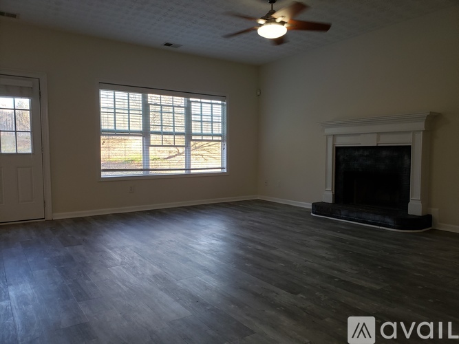 A spacious room with a fireplace and a ceiling fan.