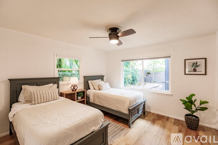 A bedroom with two beds and a ceiling fan.