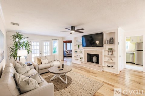 A living room with a white couch and a television on the wall.
