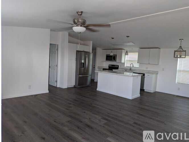 A spacious kitchen with white cabinets and a wooden floor.