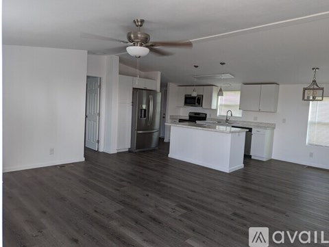 A spacious kitchen with white cabinets and a wooden floor.