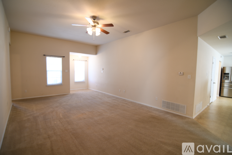 A spacious room with a ceiling fan and two windows.