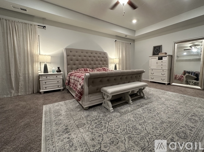 A bedroom with a large bed and a bench in the middle of the room.