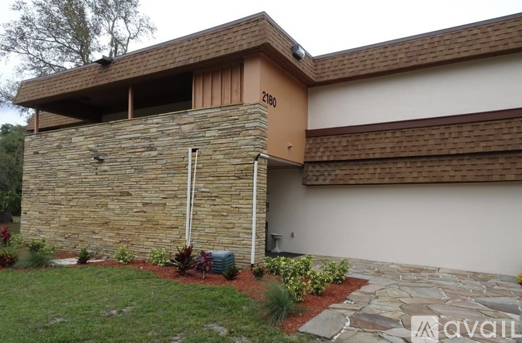 A house with a stone wall and a brown roof.