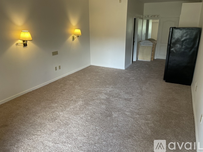 A room with a carpeted floor and two wall lamps.