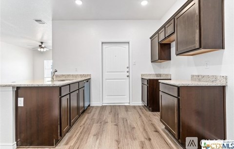 A kitchen with dark wood cabinets and a white door.