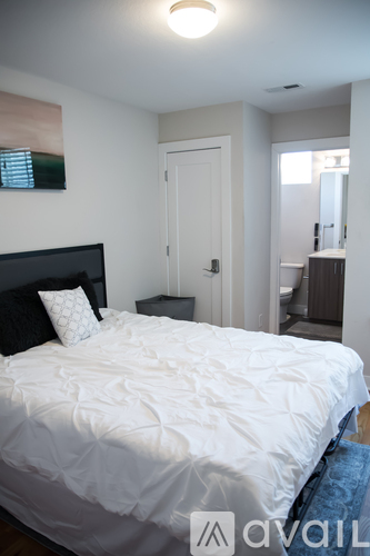 A bedroom with a white bed and a painting on the wall.