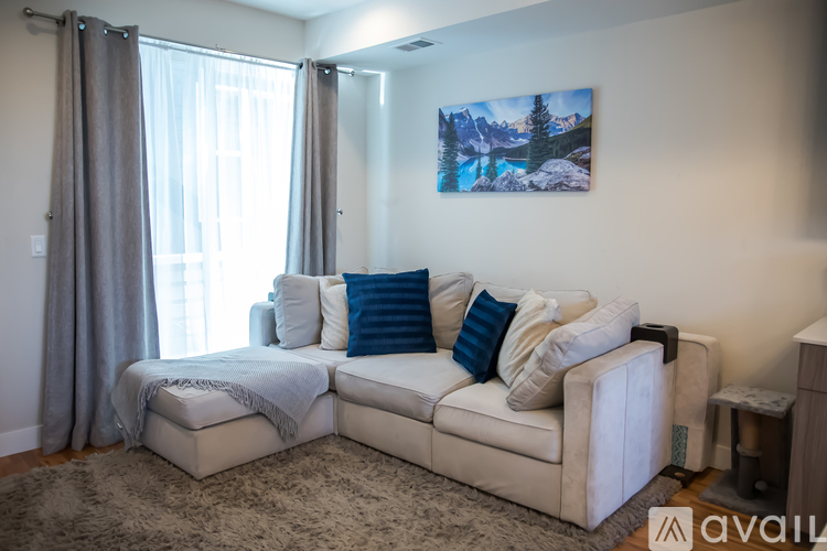 A living room with a white couch and a painting of a mountain scene on the wall.