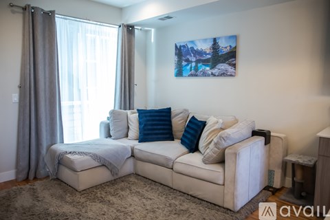A living room with a white couch and a painting of a mountain scene on the wall.