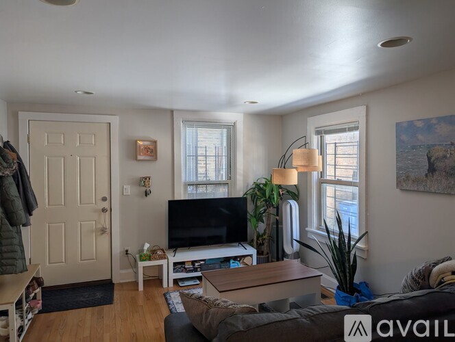 A living room with a couch, a television, a plant, and a painting on the wall.