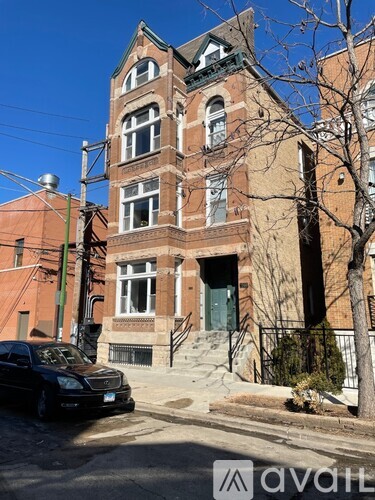 A black car is parked on the side of a street in front of a red brick building.