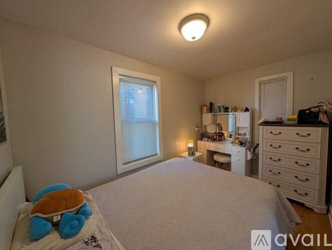 A bedroom with a bed, desk, and drawers.