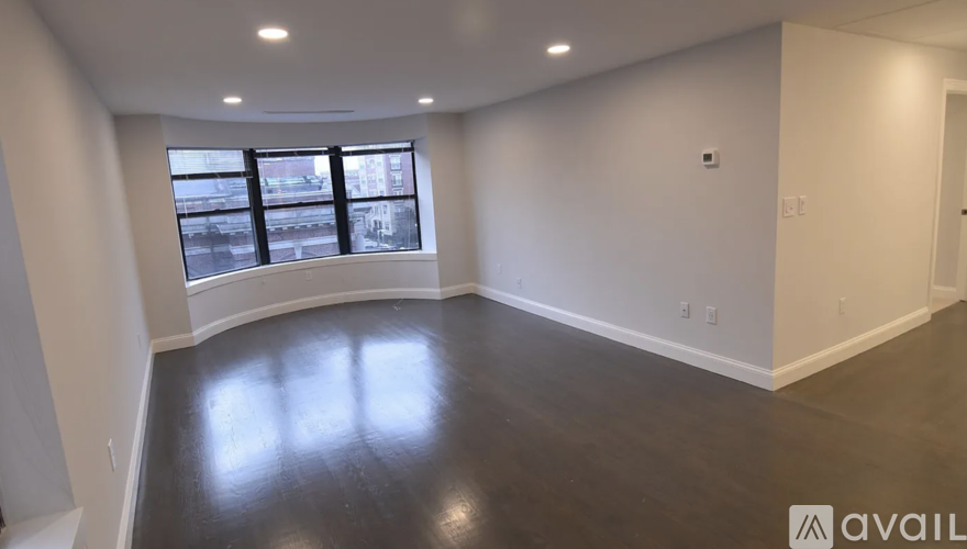 A large empty room with a window overlooking a cityscape.