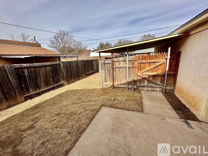 A backyard with a wooden fence and a concrete pathway.