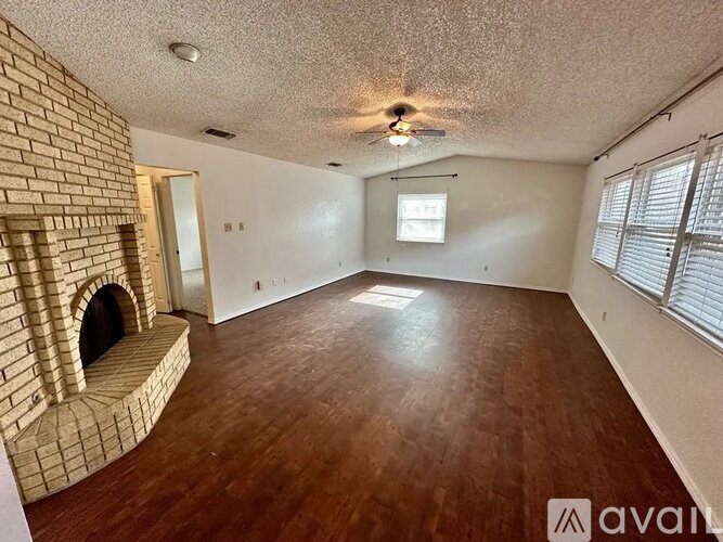A room with a brick fireplace and wooden flooring.