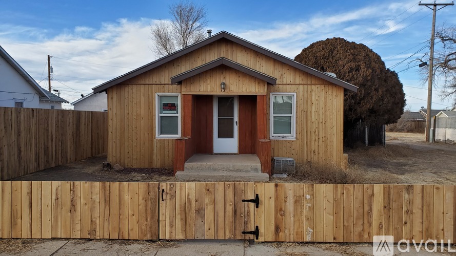 A small wooden house with a brown door and windows is for sale.