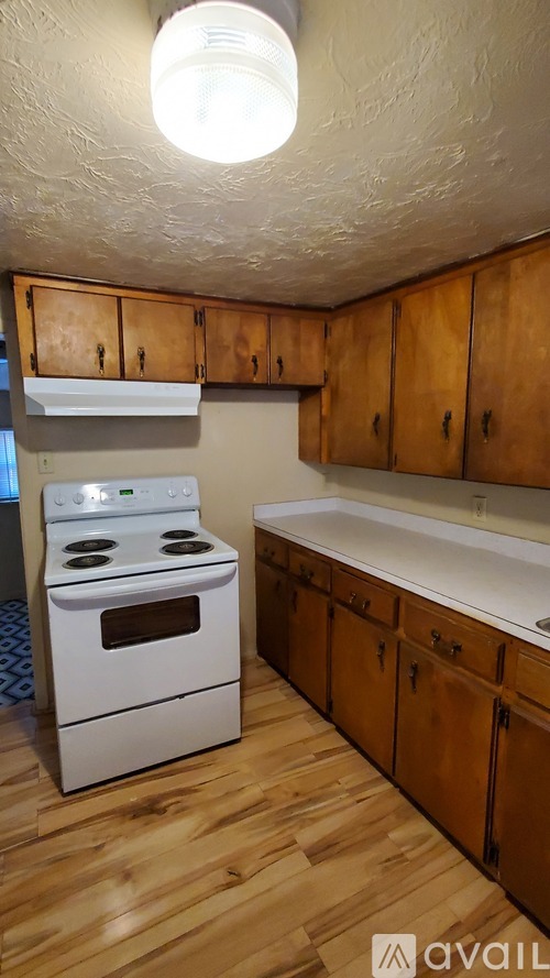 A kitchen with wooden cabinets and a white stove top oven.
