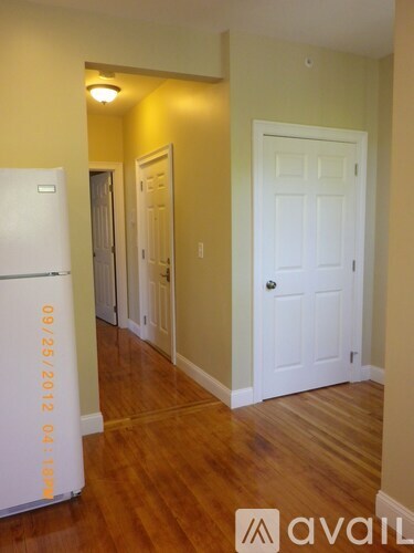 A white fridge with the date 09/25/2012 on it is in a room with wood floors and white doors.