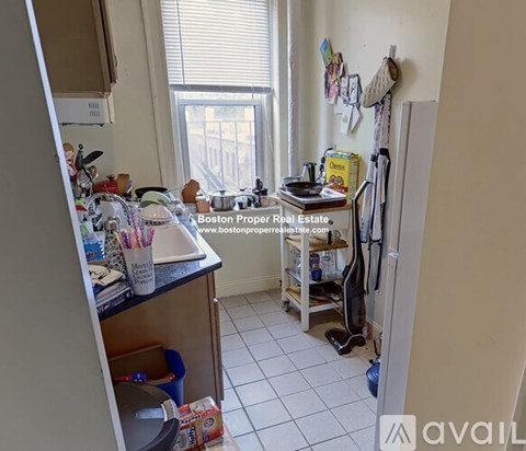 A kitchen with a refrigerator, sink, and a window with a view of a city.