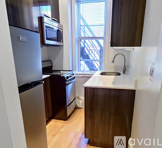 A kitchen with a refrigerator, microwave, and sink.