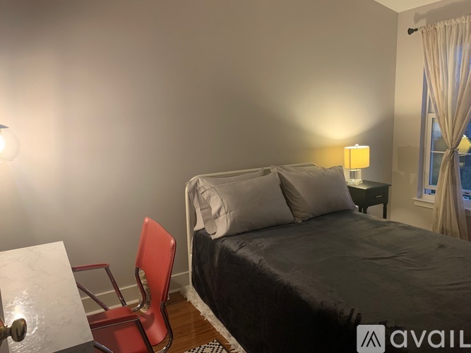 A bedroom with a bed, chair, and lamp.