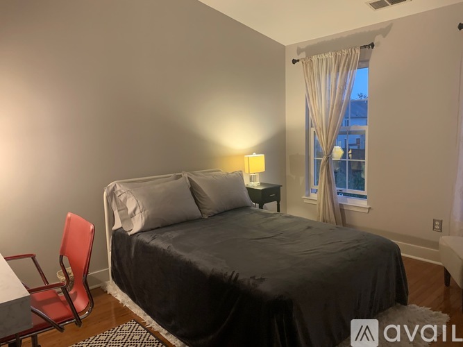 A bedroom with a bed, chair, and window.