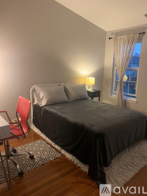 A bedroom with a bed, chair, and window.
