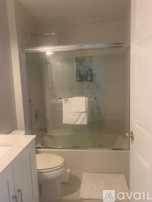 A white toilet sits in a small bathroom with a glass shower door.