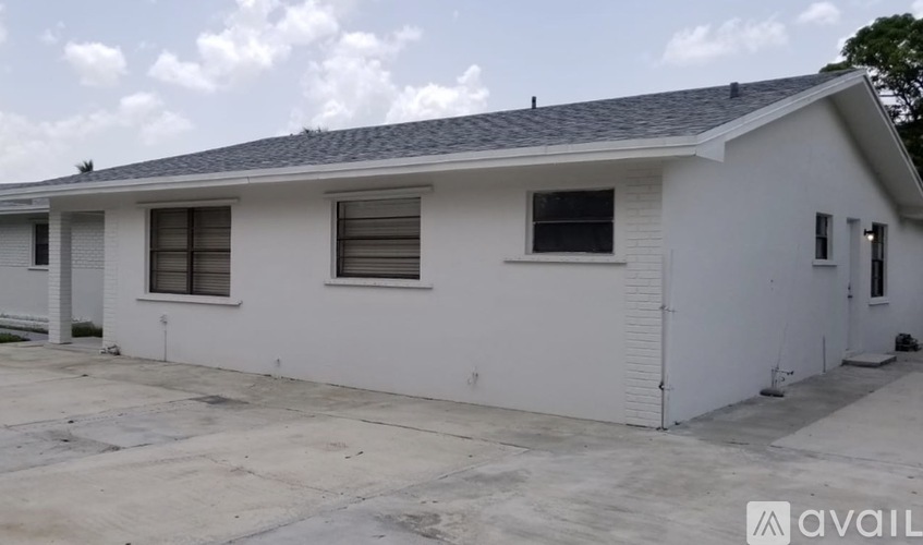 A white house with a grey roof and a sign that says "available".