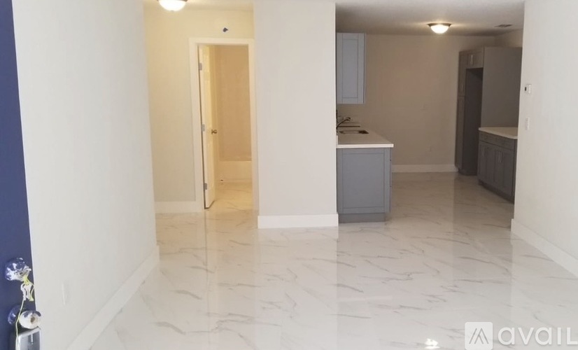 A spacious room with marble flooring and a kitchenette in the background.