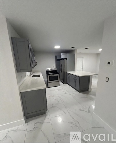 A kitchen with marble flooring and grey cabinets.