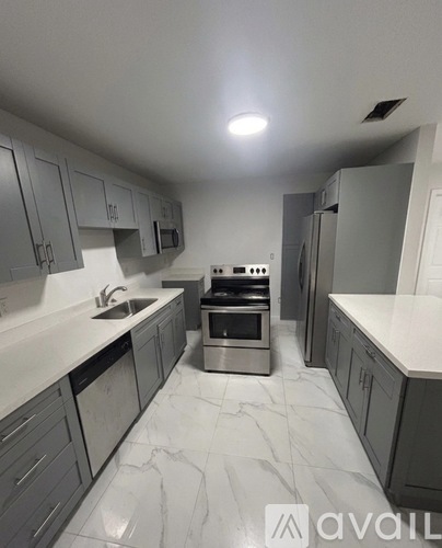 A kitchen with grey cabinets and a marble floor.