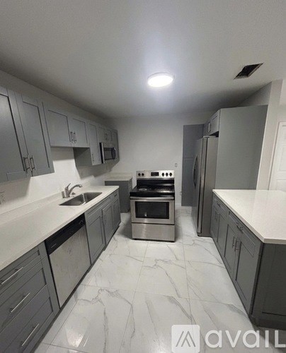 A kitchen with grey cabinets and a marble floor.