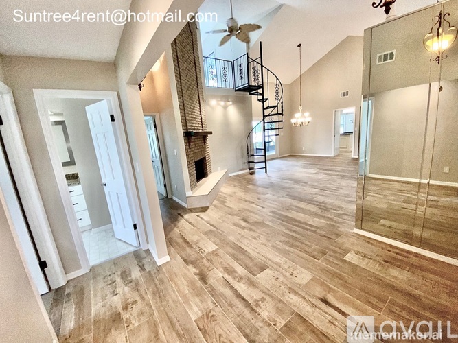 A spacious room with a staircase and a ceiling fan.