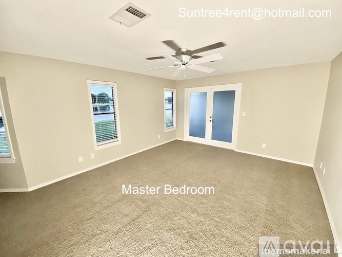 A master bedroom with a carpeted floor and a ceiling fan.