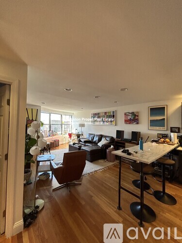 A living room with a brown leather couch and a wooden floor.