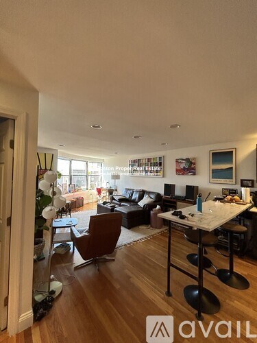 A living room with a brown leather couch and a wooden floor.