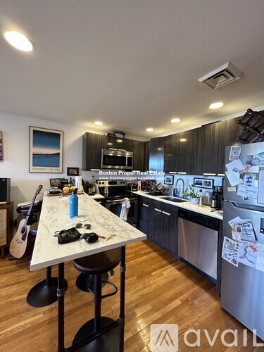 A kitchen with a marble table and a fridge with papers on it.